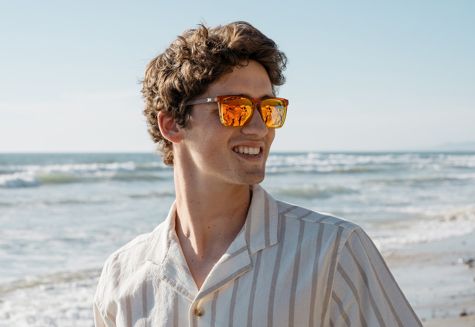 Man on the beach wearing orange sunglasses